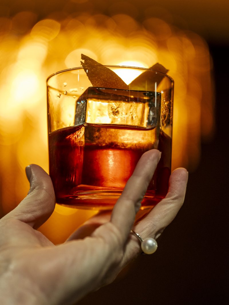 A cocktail held in warm candlelight during evening service